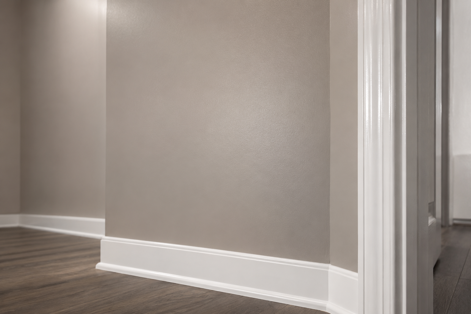 Close-up of a greige painted common-area wall showing a satin sheen next to a glossy white door frame and white baseboard