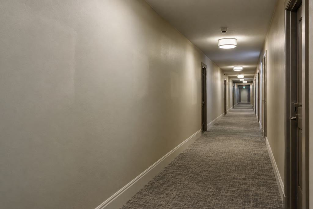 Repainted condo corridor with drywall patches showing through the paint
