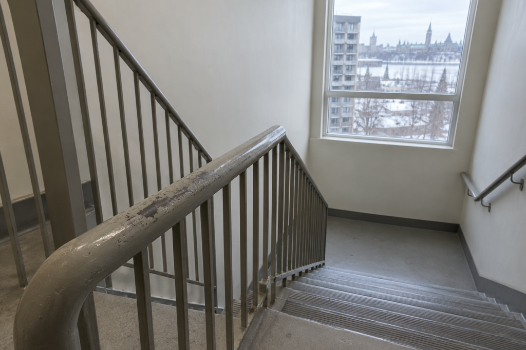 Condo stairwell with a painted metal handrail worn through in the middle