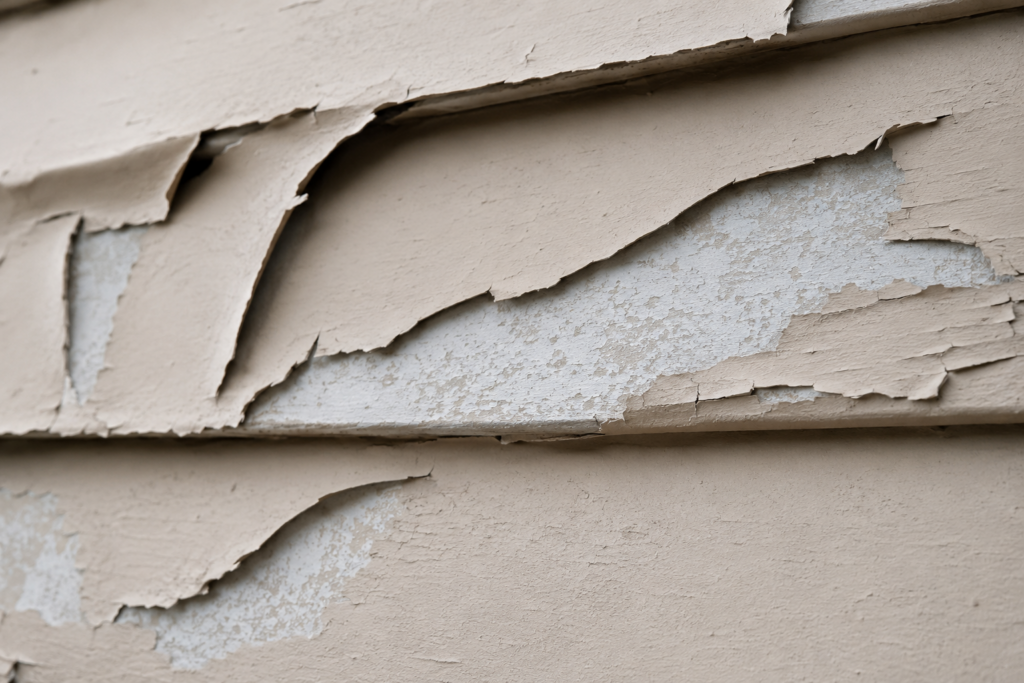 Close-up of paint curling off aluminum siding panel edges