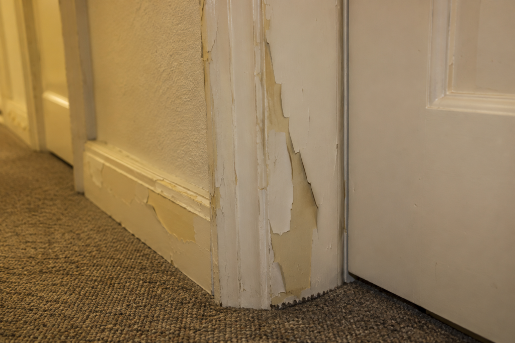 Corridor door frame with new paint peeling off old oil-based enamel