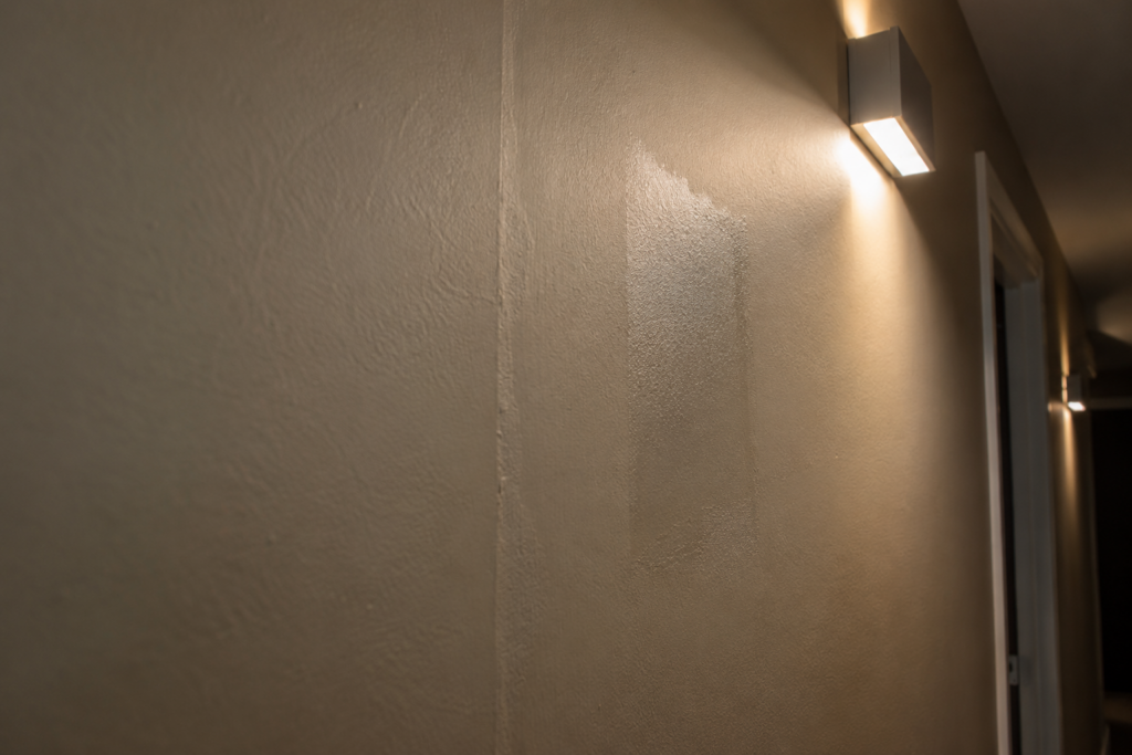 LED sconce raking light showing a drywall seam and touch-up patch